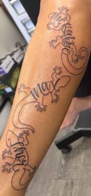 Three gecko tattoos down one arm spelling McKenszie, Max and Thor