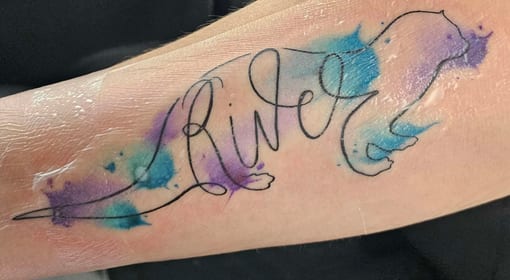Watercolour otter tattoo with the name River in calligraphy